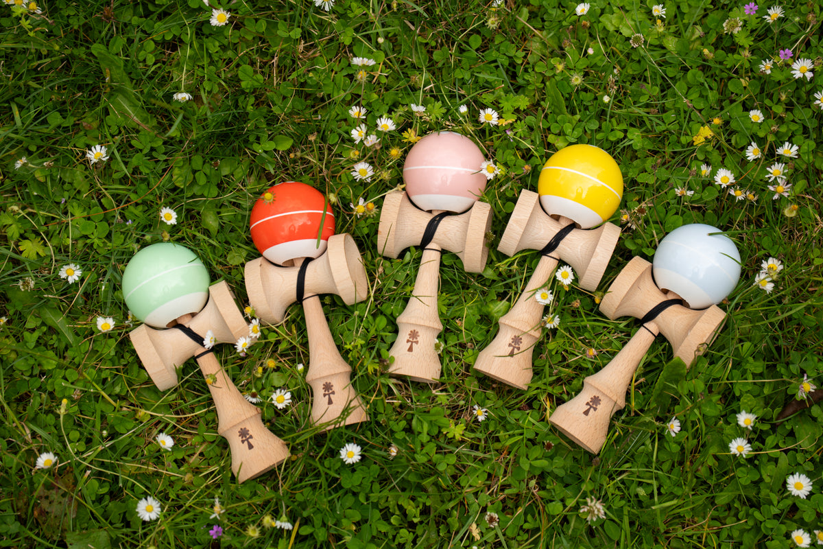 KIN BASE kendamas in five colors standing in the grass