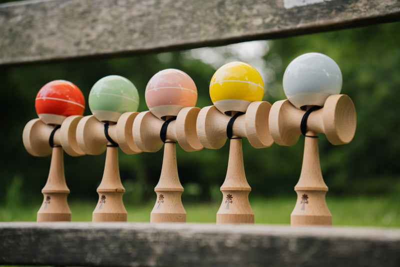KIN BASE kendamas in five colors lined up outdoors